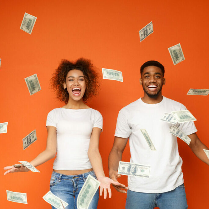 happy woman and man with cash thrown up in the air
