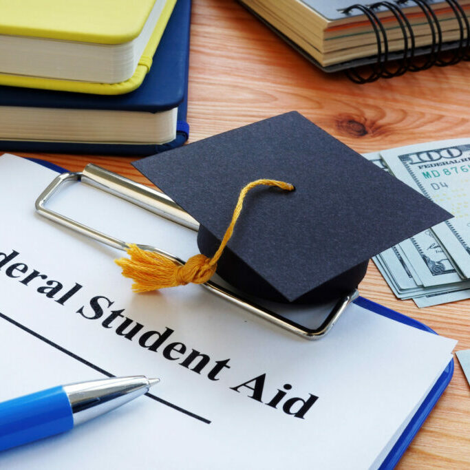 Federal student aid papers and small Square academic cap